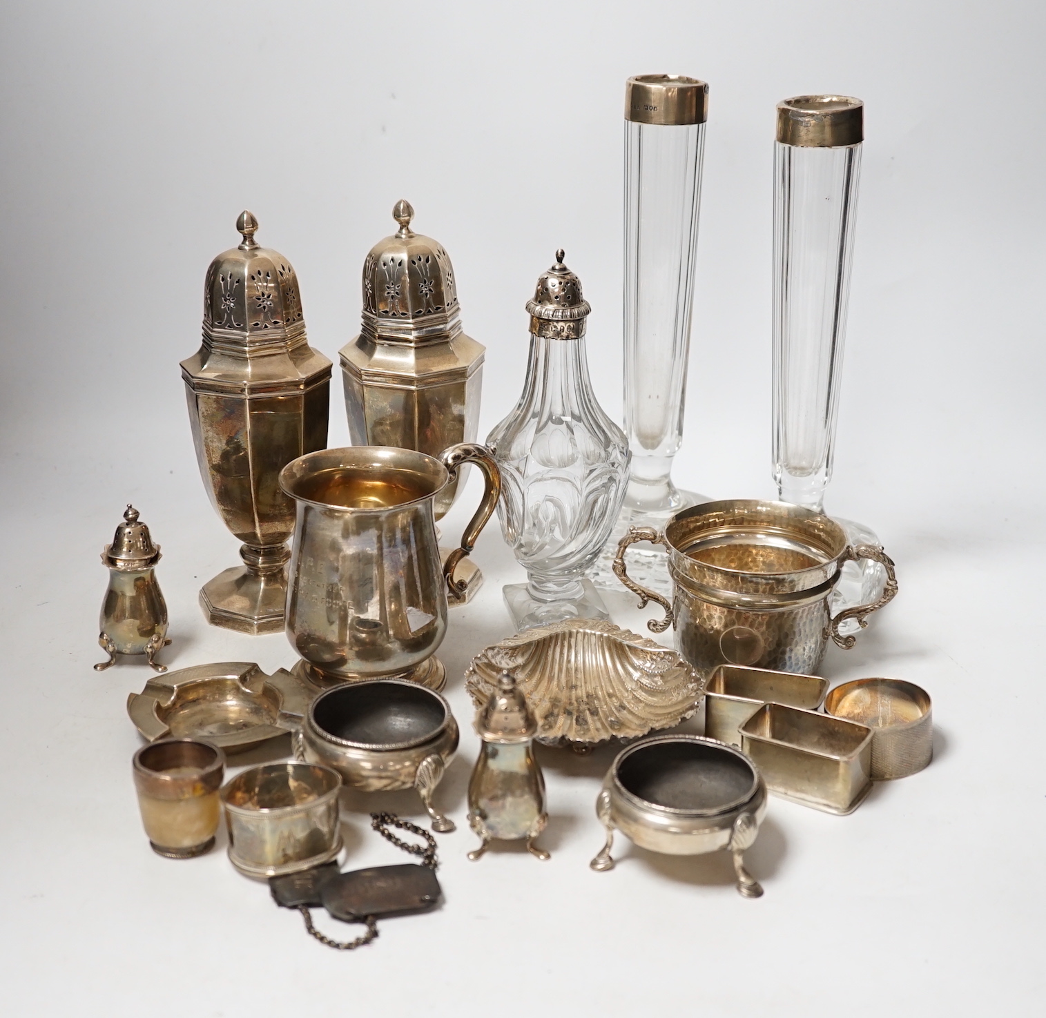 Assorted small silver including a christening mug, a planished porringer, pair of George V sugar casters, butter shell, ashtray, two mounted glass posy vases, four condiments, four napkin rings, a mounted glass cruet bot